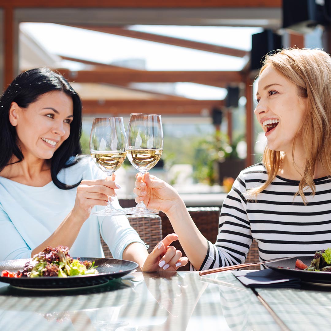 two women toasting glasses of wine during a meal