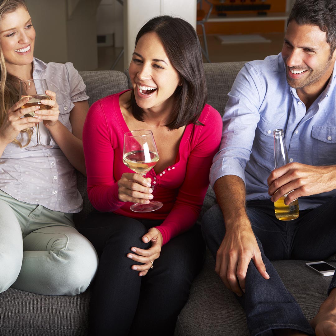 group of friends sitting on a couch holding alcoholic beverages